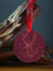 Round metal ornament featuring detailed rose gold etching of a stag's profile with antlers, surrounded by winter foliage and stars on burgundy background. 3.5-inch diameter piece with crimson ribbon. Double-sided woodland artwork.