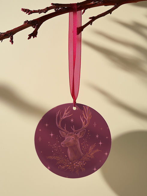 Round metal ornament featuring detailed rose gold etching of a stag's profile with antlers, surrounded by winter foliage and stars on burgundy background. 3.5-inch diameter piece with crimson ribbon. Double-sided woodland artwork.