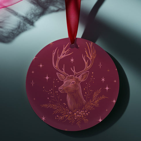 Round metal ornament featuring detailed rose gold etching of a stag's profile with antlers, surrounded by winter foliage and stars on burgundy background. 3.5-inch diameter piece with crimson ribbon. Double-sided woodland artwork.