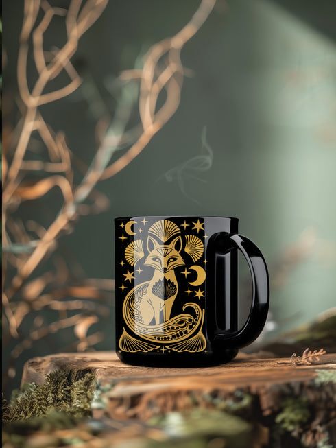 A black ceramic mug featuring a stylized golden fox design surrounded by Art Deco ginkgo fans, crescent moons, and stars. The mug has a glossy finish and ergonomic handle.