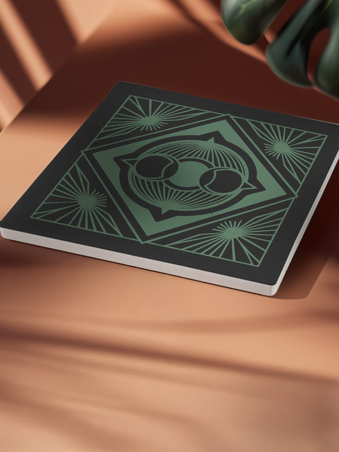 A black and emerald green ceramic coaster featuring a triple moon motif with celestial art deco sunbursts.