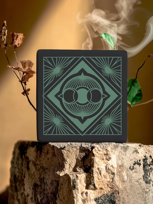 A black and emerald green ceramic coaster featuring a triple moon motif with celestial art deco sunbursts.
