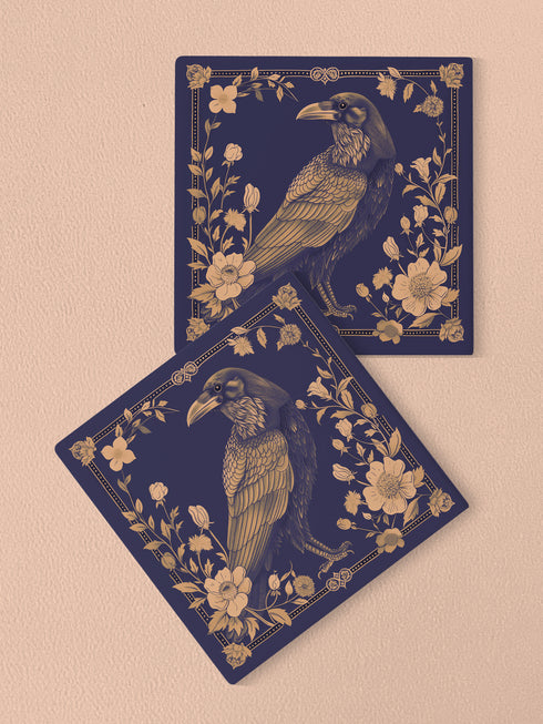 Square ceramic coaster featuring detailed illustration of a raven surrounded by golden florals and botanicals on navy background. Decorative border with dotted pattern frames the design.