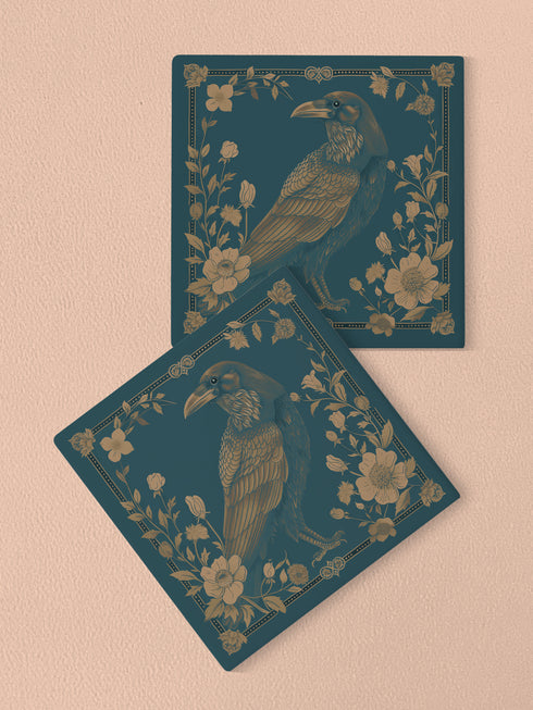 Square ceramic coaster featuring detailed gold raven illustration surrounded by botanical elements on emerald green background, with ornate border design and cork backing.