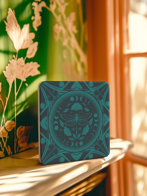 Square ceramic coaster featuring a detailed emerald green dragonfly illustration centered in a medallion, surrounded by moon phases and Art Nouveau patterns on a dark background.