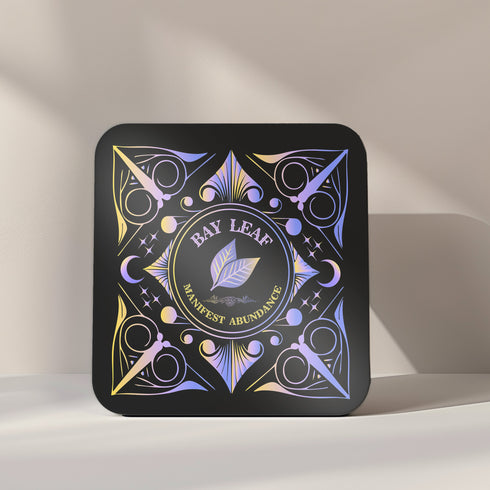 A 4-piece wealth-themed coaster set featuring intricate, gold and black designs with iridescent accents. Each coaster is dedicated to a different herb or spice, including basil, bay leaf, cinnamon, and mint, each symbolizing prosperity, abundance, riches, and wealth. The designs feature celestial motifs and geometric patterns, adding a mystical and luxurious touch to the coasters.