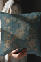 Teal throw pillow cover featuring a golden raven illustration surrounded by intricate floral designs, suitable for gothic or dark academia decor.