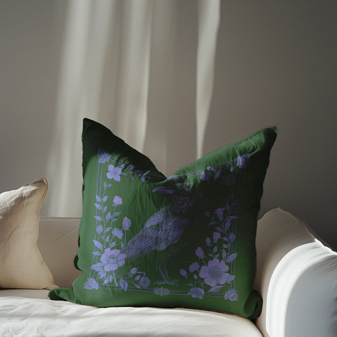 Emerald green throw pillow cover featuring a violet raven illustration surrounded by intricate floral designs, perfect for gothic or dark academia decor.