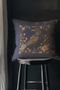 Navy blue throw pillow cover featuring a bronze raven illustration surrounded by intricate floral designs, suitable for gothic or dark academia decor.