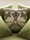 A square decorative throw pillow by Grimoire and Goblet featuring a woven jacquard tapestry design. The pattern displays two regal white swans facing each other with curved necks forming a heart shape, set against a dark background rich with intricate floral botany in beige, dusty rose, and sage green tones. The texture is thick and fabric-like, mimicking vintage needlepoint or Arts and Crafts style. The pillow is stuffed and sewn shut without a visible zipper.