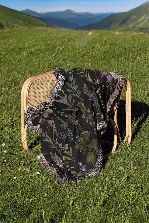 Forest green cotton throw blanket with woven silver moon phases and golden sun motifs, finished with multicolored fringe trim.