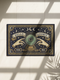 Grimoire and Goblet witchy doormat featuring a deep navy background with antique gold faux embroidered design of a crystal ball with central eye, surrounded by crescent moons, stars, and pointing hands, with ornate border and banner details, rectangular entryway rug with black trim and non-slip backing, mystical occult home decor mat for indoor or covered outdoor use