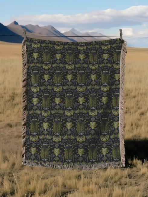Luxurious woven cotton throw blanket featuring symmetrical scarab beetle pattern in olive green on black background with white fringe trim. Perfect for dark academia, gothic, or cottagecore decor as wall hanging or cozy throw. Mystical home gift.