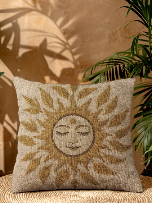 A square woven tapestry throw pillow in neutral earth tones of beige and gold. The pillow has a rich, textured surface from its jacquard weave. The design features a large, central celestial sun face with closed eyes, a serene smile, and a third eye symbol on its forehead. The sun's rays are stylized as intricate leaves, blending botanical and solar motifs. The pillow is made from a durable cotton and polyester blend, giving it a high-quality, artisanal feel.