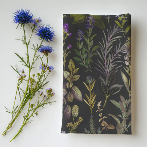 set of four dark charcoal cloth napkins with a repeating pattern of muted purple, green, and gold herbs and flowers in an elegant botanical design.