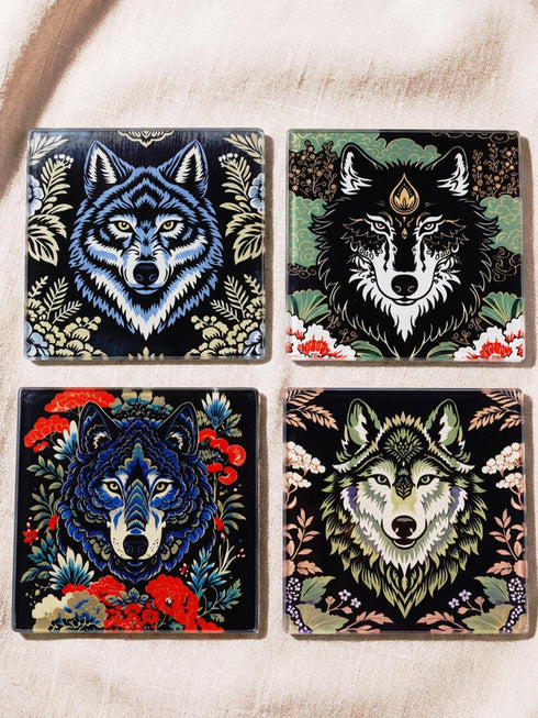 Set of 4 square tempered glass coasters featuring a mystical wolf design on a black background. High-gloss finish with non-slip rubber feet. Dark Academia and Whimsigoth aesthetic home decor. Close-up detail shows grey wolf fur texture and amber eyes. Durable drinkware protection for wooden tables. Grimoire and Goblet gothic luxury barware accessory for coffee tables and desks. Heat resistant glass surface with polished edges.