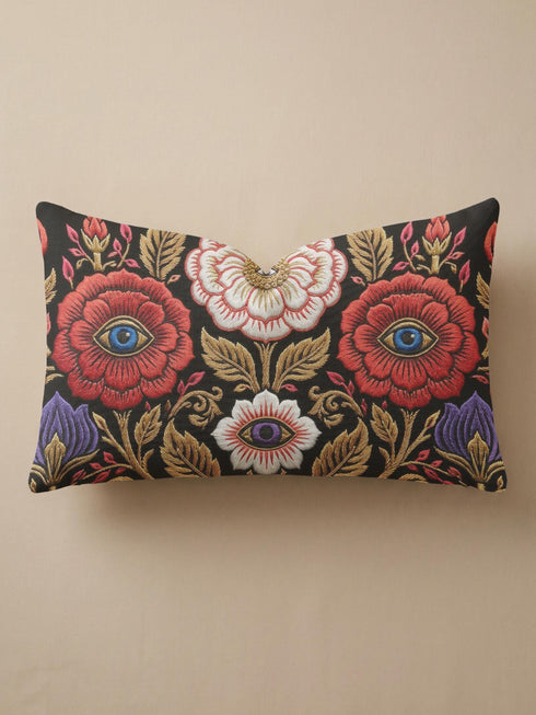 Evil eye lumbar pillow cover in black featuring a symmetrical folk art floral print. Two crimson red roses hold bright blue eyes at their centers, a white blossom below cradles a violet purple eye, and antique gold leaves, scrollwork, and pink buds frame the design. Purple tulips anchor the lower corners. Rectangular 20 x 12 inch cushion case with a hidden zipper and the double sided embroidered look design printed on smooth, soft, linen feel polyester fabric.