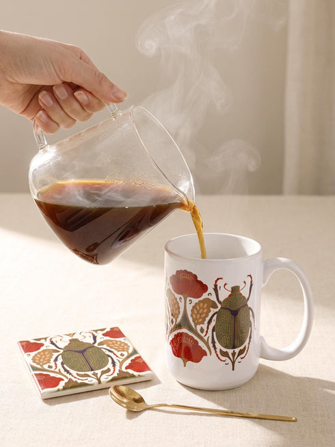 A luxury gift set featuring a matching ceramic mug and square coaster with a vintage entomology design. The artwork depicts a vibrant green Scarab beetle with iridescent wings, surrounded by dark moody floral botanicals in rust and ochre, set against a creamy background in a Victorian naturalist style. The mug is 15oz with a large handle and full wrap design. The coaster is glazed ceramic tile with a cork backing. Perfect for Dark Academia and Grimoire and Goblet gothic home decor.