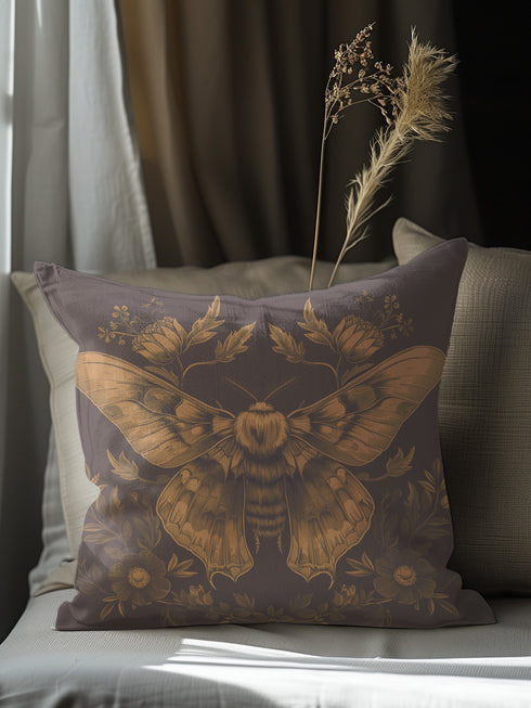 A decorative pillow cover featuring an intricately detailed Luna moth illustration in antique gold on a smoke gray background, surrounded by symmetrical botanical elements including flowers and delicate foliage.