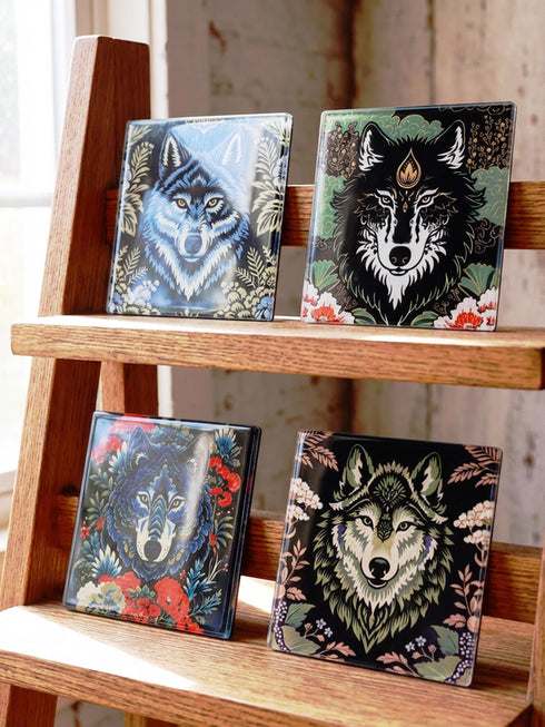 Set of 4 square tempered glass coasters featuring a mystical wolf design on a black background. High-gloss finish with non-slip rubber feet. Dark Academia and Whimsigoth aesthetic home decor. Close-up detail shows grey wolf fur texture and amber eyes. Durable drinkware protection for wooden tables. Grimoire and Goblet gothic luxury barware accessory for coffee tables and desks. Heat resistant glass surface with polished edges.