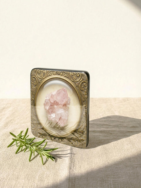 Grimoire and Goblet set of four square glossy coasters featuring high-resolution printed illustrations of raw crystals: purple amethyst, pink rose quartz, iridescent labradorite, and banded agate. Each gemstone is depicted inside a printed faux antique brass baroque frame with intricate scrollwork, set against a cream parchment background. The design is a flat 2D trompe l'œil print on hardboard, creating a realistic 3D specimen box illusion.