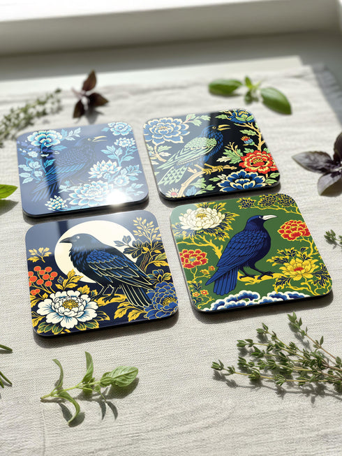Grimoire and Goblet set of 4 glossy square coasters featuring Chinoiserie style raven illustrations. 1: Navy blue with blue floral pattern and raven. 2: Navy background with black raven, white full moon, and red berries. 3: Moss green background with blue bird and yellow chrysanthemums. 4: Black background with teal-winged raven and red peonies. MDF hardboard with cork backing. Flat vector botanical art style.