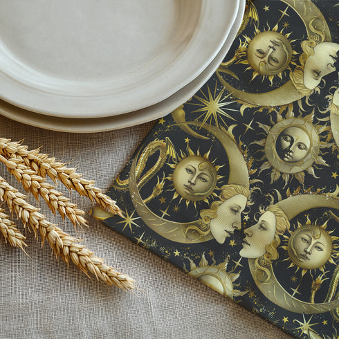 Set of four black cloth napkins with a repeating pattern of golden sun and moon faces, surrounded by swirling flames, craters, and scattered stars.moon