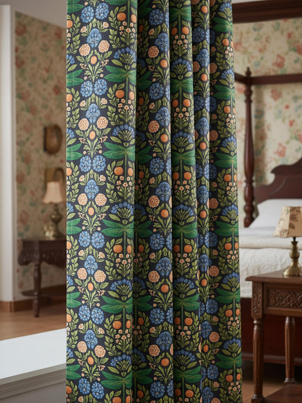 A single curtain panel made of smooth, heavyweight blackout fabric with a subtle satin sheen. The repeating vertical design features a symmetrical, Arts and Crafts style botanical pattern on a dark charcoal background. The central motif includes large, stylized green dragonflies with horizontal wings, surrounded by intricately woven green leaves and stems. Clusters of dusty blue, rounded flowers and muted rust-orange blooms complete the dense, floral damask layout. The back is solid white.