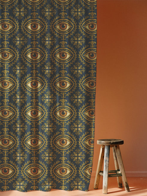 A single panel of a heavyweight blackout curtain with a rich, satiny texture. The design features a repeating pattern of a realistic, all-seeing evil eye, each framed within an ornate, golden Victorian botanical flourish on a dark charcoal background. This mystical art is ideal for Dark Academia, Gothic, and Witchy interior aesthetics, providing both a dramatic statement piece and functional light-blocking for a bedroom, library, or sacred space.