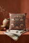 Square 17 by 18 inch jacquard woven throw pillow, woven identically on both faces and closed with a clean finished edge. A large detailed scarab beetle in black, gold, and dark brown sits at the center inside a dotted circular border, surrounded by symmetrical Art Nouveau vines and cream lotus flowers on a rust red ground. Small white floral motifs sit in each corner. The design is woven flat into the cotton blend cloth, with visible thread texture and a soft sheen in the ground.