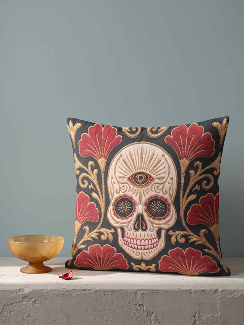 Square pillow cover in smooth linen-like polyester with a concealed bottom zipper, printed on both faces to imitate hand embroidery and tapestry, with no stitching or raised texture. On a charcoal black ground, an ivory skull carries an open radiating third eye on its brow, with golden starbursts glowing in its eye sockets. Crimson fan shaped botanical blooms spread around the skull, framed by antique gold acanthus scrollwork that curls toward each corner of the cover.